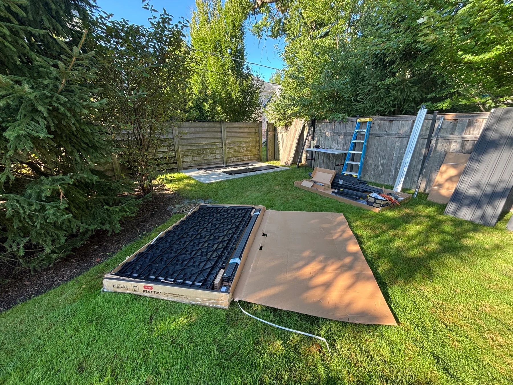 Before assembly: packaged panels and other shed components laid out near the installation area.