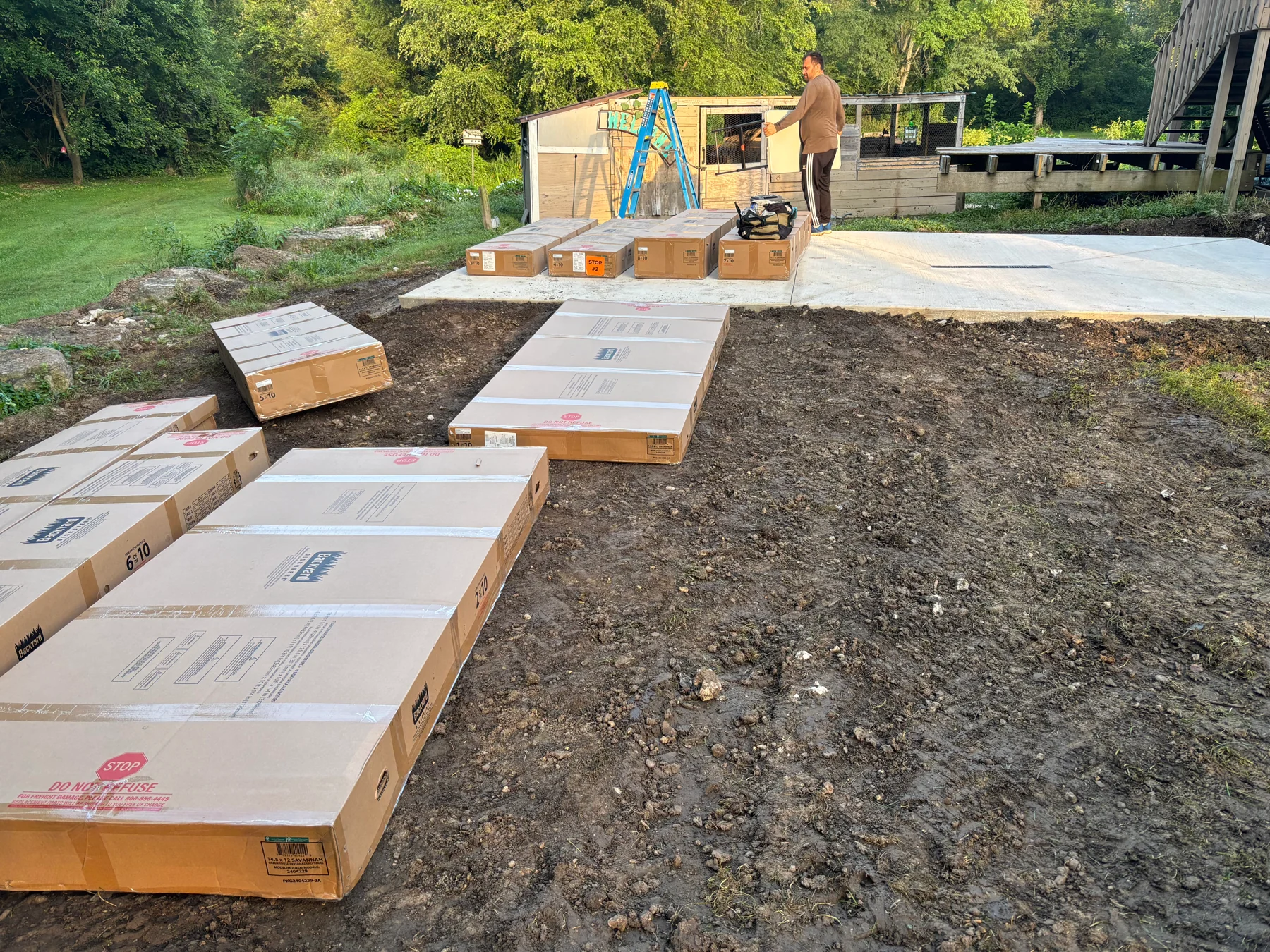 Before assembly: the greenhouse components in numbered boxes around the installation area.